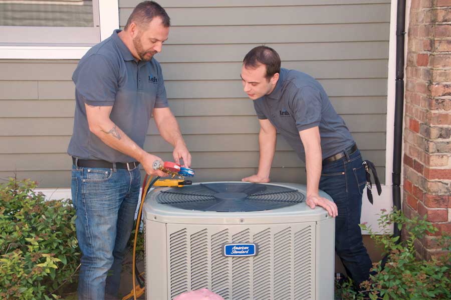 Technicians performing AC coil cleaning service in Elgin IL home backyard